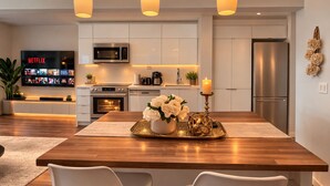 A modern kitchen with white cabinetry, a built-in microwave, a stainless steel refrigerator, and a flat-screen TV displaying Netflix. - 2 Bedroom Luxury Apartment in Downtown Toronto (Toronto)