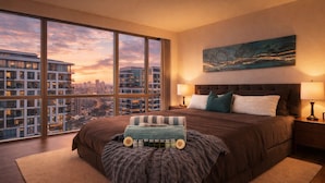 A modern bedroom with a large bed, a view of a cityscape, and a painting on the wall. - 2 Bedroom Luxury Apartment in Downtown Toronto (Toronto)