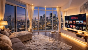 A modern living room with a large TV, a cozy sofa, a small table, and a city view. - 2 Bedroom Luxury Apartment in Downtown Toronto (Toronto)