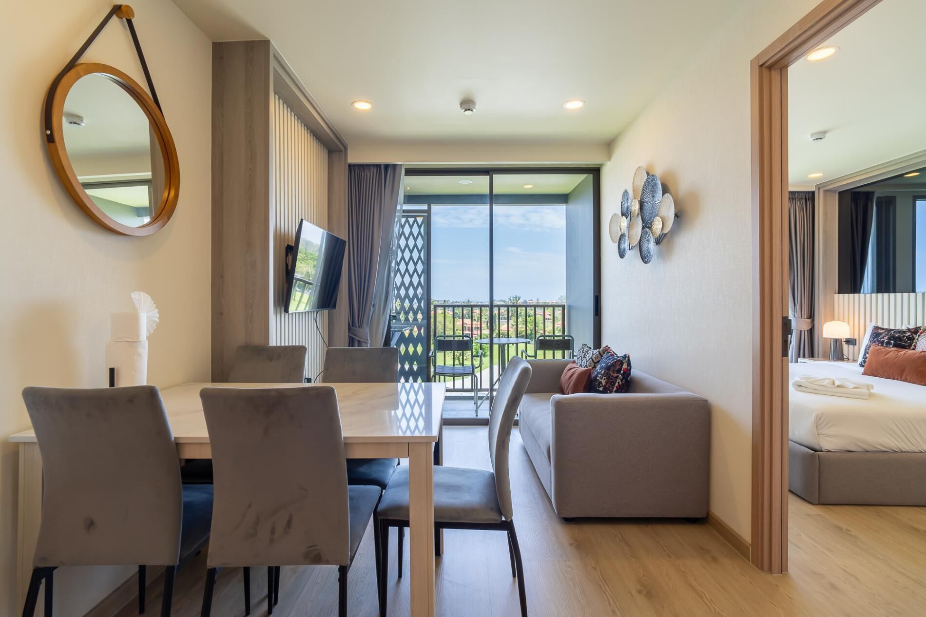 Une chambre d’hôtel moderne dotée d’un balcon, d’un coin repas avec des chaises et une table, d’un canapé et d’un lit.