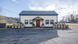 A white building with a red door, two windows, and a sign reading 'Saratoga Vineyards.' - Saratoga Vineyard + Private Golf Course + Tavern - Sleeps 25 (Greenwich)