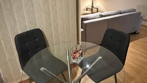 Ein modernes Wohnzimmer mit einem Glastisch, schwarzen Stühlen, einem grauen Sofa und einer Lampe.