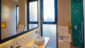 A modern bathroom with a large mirror, a round sink, a shower, and a green brick wall. - Baberrih (Moulay Bouzarqtoune)