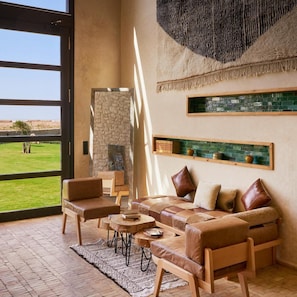 Amplia sala de estar con un ventanal grande, pared de piedra, chimenea y una mesa de centro de madera.