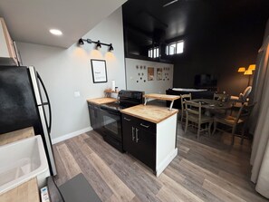 A modern kitchen with a stove, oven, and wooden countertop. There is a dining area with a table and chairs.