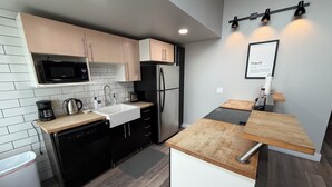 A modern kitchen with a built-in microwave, sink, and black refrigerator.