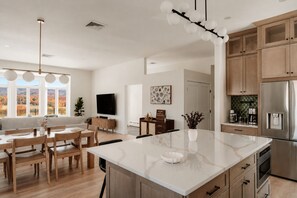 A modern kitchen with a large island, wooden cabinets, and a built-in oven.