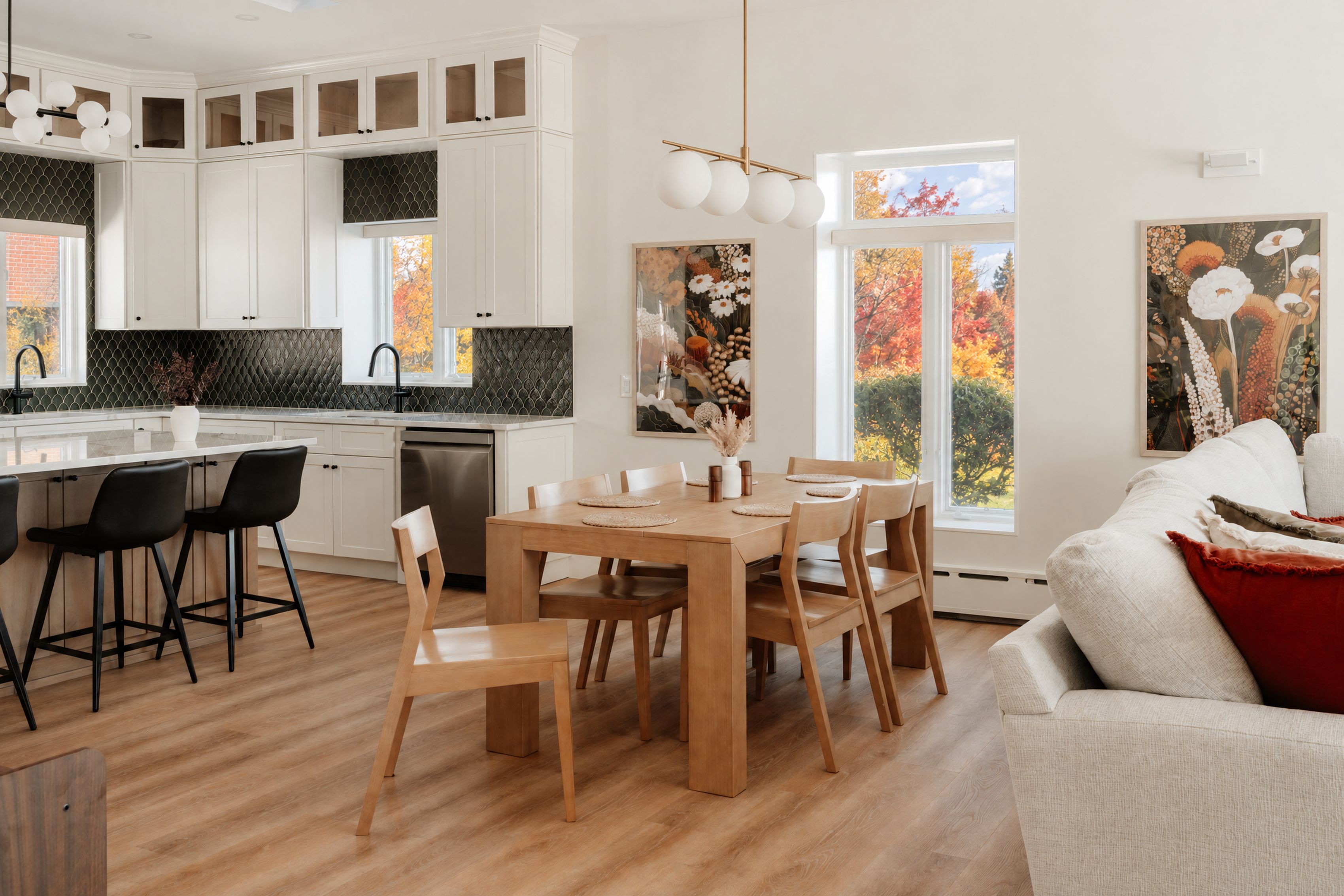 Une cuisine moderne avec des meubles blancs, une table à manger en bois et des chaises noires.