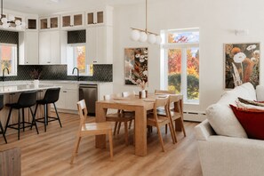 A modern kitchen with white cabinets, a wooden dining table, and black chairs.