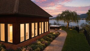 A house with large windows, a patio, and a view of a lake.