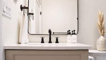 Een badkamer met een wit wastafel, zwarte kraanwerk, een spiegel en een toilet.