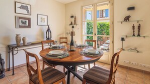 Un coin repas avec une table ronde, des chaises et une vue sur un jardin, accessible par une porte vitrée.