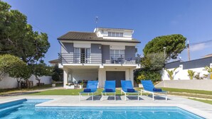 A two-story house with a swimming pool, blue lounge chairs, and a covered patio. - Mi Capricho by Interhome (Calafell)