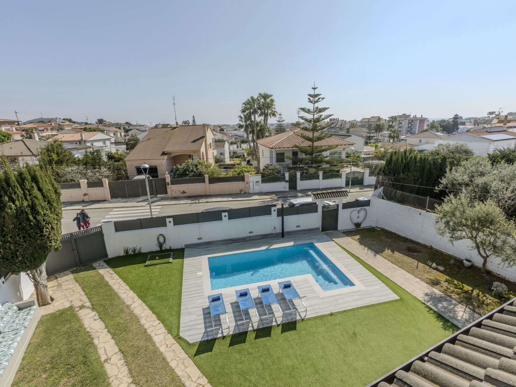 A residential area with a swimming pool, a well-maintained lawn, and a view of neighboring houses.