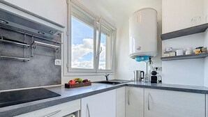 Eine Küche mit Fenster, Spüle, Wasserkocher und Mikrowelle.