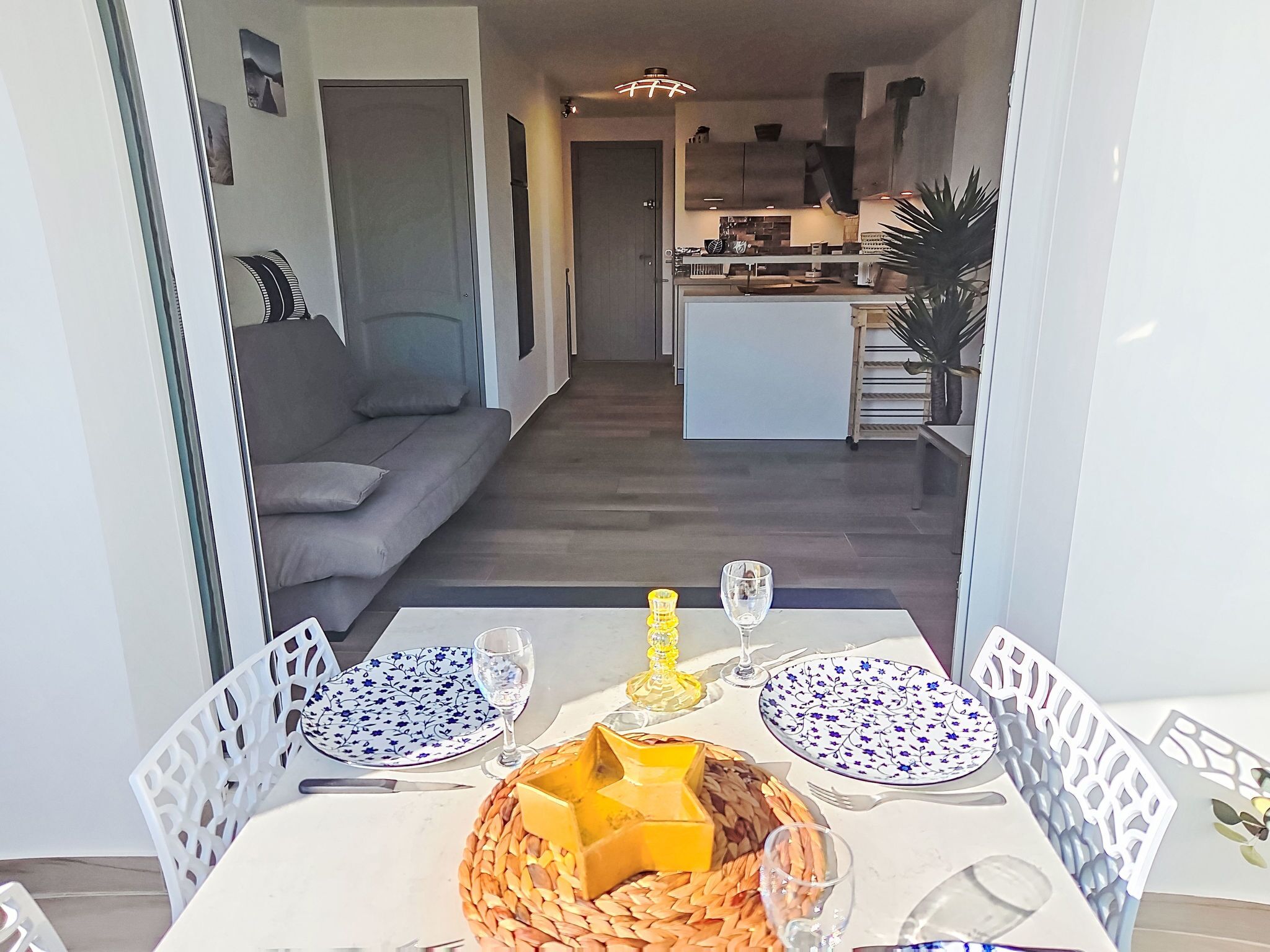 Een eetgedeelte met een tafel gedekt voor twee personen, met een geweven mand met kaas, twee borden met een patroon en een glas water.