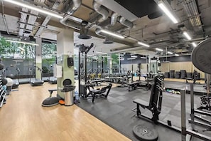 A gym with various exercise equipment, large windows, and a wooden floor. - Fully furnished 1-bedroom apartment in a prime Wembley location (Wembley)