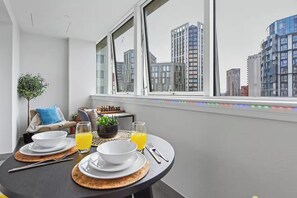 A dining area with a table set for two, two glasses of orange juice, white plates, and a small potted plant. - Fully furnished 1-bedroom apartment in a prime Wembley location (Wembley)