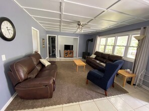 A living room with a brown leather sofa, a blue armchair, a wooden coffee table, and a television.