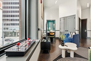 Ein modernes Wohnzimmer mit großem Fenster, einem blauen Sofa, einem kleinen Tisch und einer Zimmerpflanze.