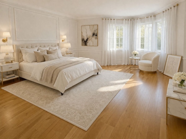 A bedroom with a large bed, bedside tables, a chair, a small table, and a window with curtains.