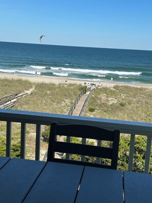 A beach view from a wooden deck with a chair, a wooden walkway leading to the beach, and the ocean in the background. - Mayor's Oceanfront Penthouse 4BR w/Elevator in Carolina Beach (Carolina Beach)