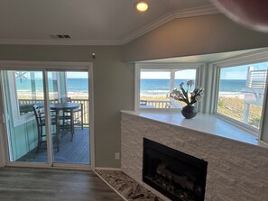 A living room with a fireplace, a dining area with a view of the beach, and a large sliding glass door. - Mayor's Oceanfront Penthouse 4BR w/Elevator in Carolina Beach (Carolina Beach)