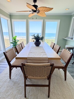 A dining area with a view of the beach, a ceiling fan, and wicker chairs. - Mayor's Oceanfront Penthouse 4BR w/Elevator in Carolina Beach (Carolina Beach)