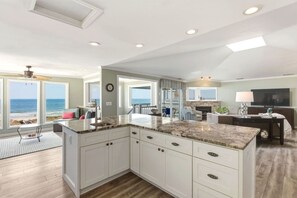 A spacious kitchen with a large island, a dining area with a view of the ocean, and a living room with a fireplace. - Mayor's Penthouse: Oceanfront luxury w/elevator 4BR (Carolina Beach)
