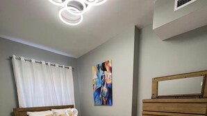 Makuuhuoneessa on puinen sänky, lipasto, seinällä oleva taulu ja kattovalaisin.