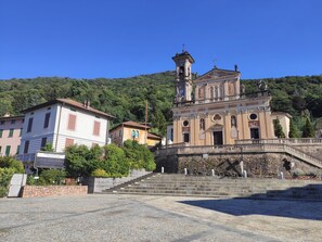 Un edificio storico con una torre dell'orologio, una scalinata che conduce all'ingresso e una piazza lastricata.