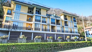 Un hotel a più piani con balconi, un'area di parcheggio e un siepe curata.