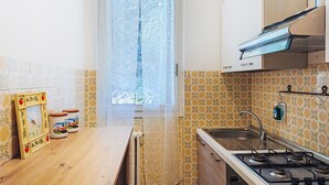 Una cucina con piano cottura a gas, lavello e finestra con vetro acidato.
