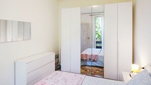Una camera da letto con un letto, un comodino, un armadio e uno specchio.