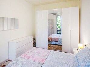 Een slaapkamer met een bed, nachtkastje, kledingkast en spiegel.