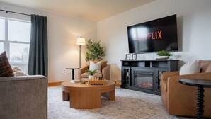 Un salon avec une cheminée, un téléviseur et une table basse.
