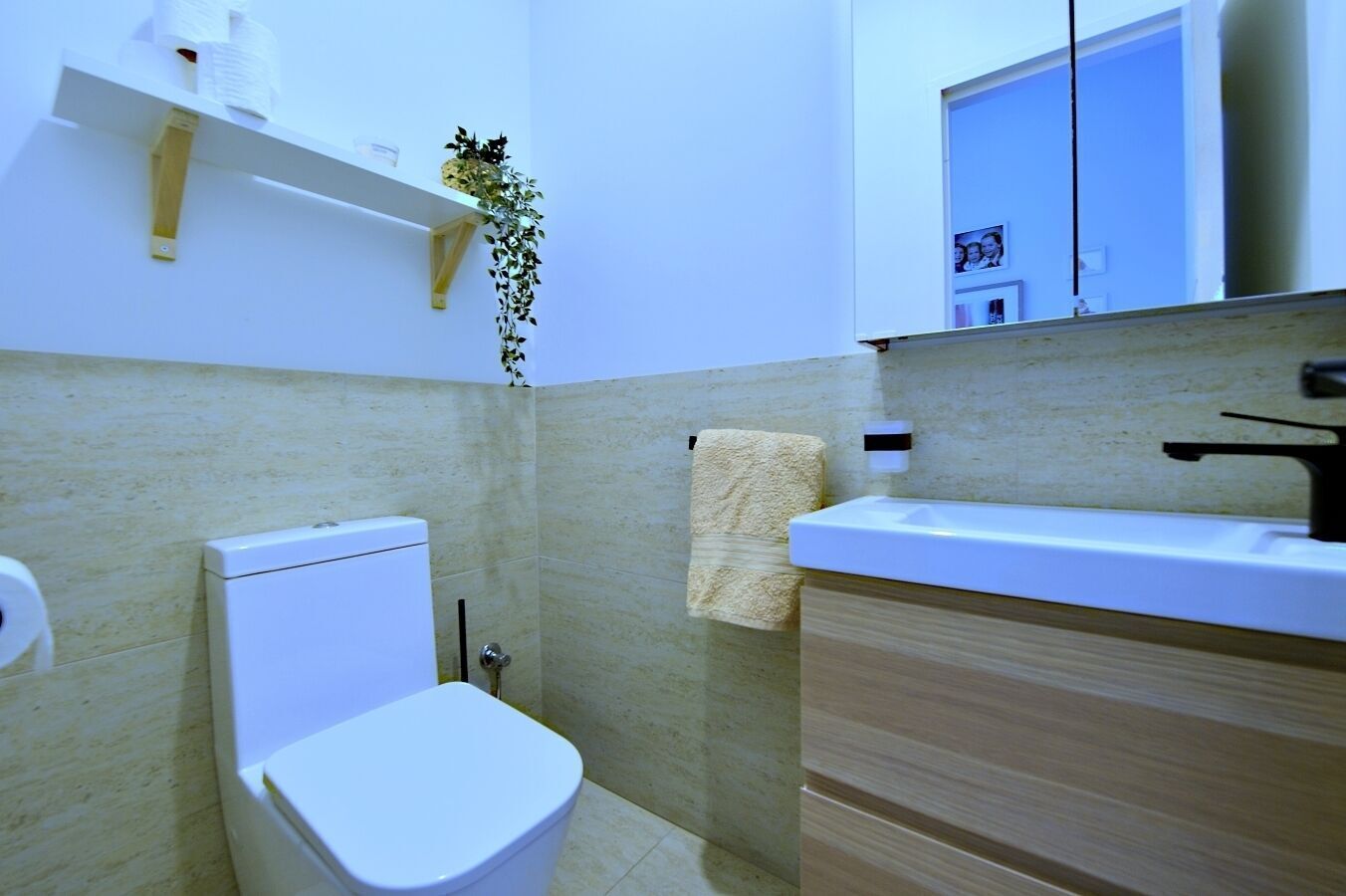A small bathroom with a toilet, a sink, and a mirror.