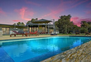 A modern pool area with clear blue water, a glass-enclosed structure, and outdoor seating.