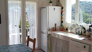 Una cocina con refrigerador, lavaplatos y ventana.