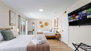 Une chambre d’hôtel avec deux lits, un téléviseur fixé au mur permettant d’accéder à des services de diffusion en continu, et un plancher en bois.