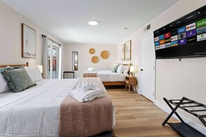 A hotel room with two beds, a TV mounted on the wall displaying streaming services, and a wooden floor. - Grand Luxe Escape w/ 6 BR, Pool, Hot Tub, & Games! (North Las Vegas)