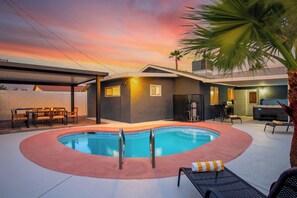 A modern house with a swimming pool, outdoor furniture, and a covered patio area. - Modern 5BR Haven w/ Pool, Hot Tub, & Pool Table! (North Las Vegas)