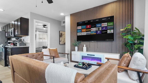 Een moderne woonkamer met een flatscreen televisie aan de wand, een bank en een salontafel.