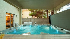 Ein Whirlpool mit einer gefliesten Terrasse, einer Ziegelwand und einer Glastür.