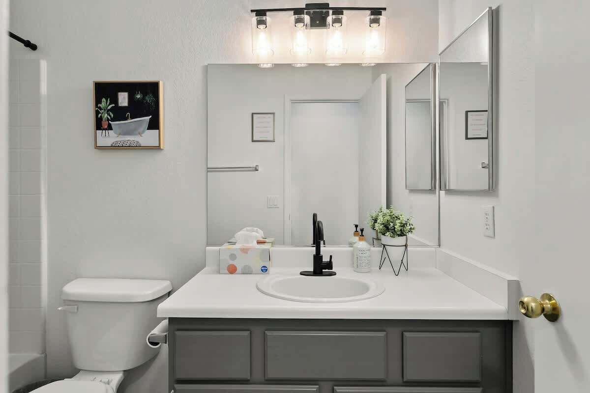 A bathroom with a white sink, a mirror, and a framed picture on the wall.