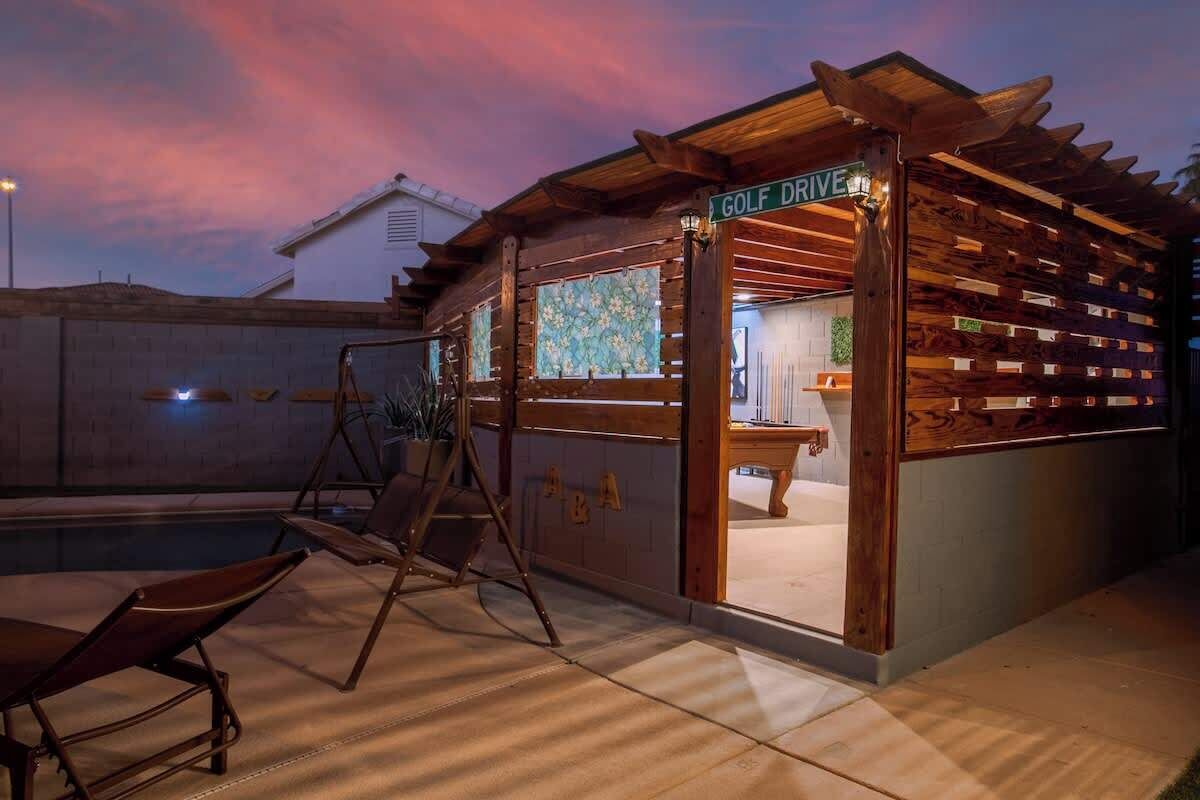 A wooden structure with a sign reading 'GOLF DRIVE,' a pool, and a swing set.