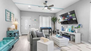 A modern living room with a sofa, coffee table, TV, and a ceiling fan.