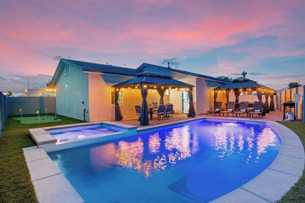 A swimming pool with a patio area, outdoor seating, and a covered section. - Jackpot 6BR w/ Arcade • Vegas Fun Near the Strip (North Las Vegas)