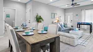 A modern living room with a dining area, a sofa, a coffee table, and a ceiling fan.