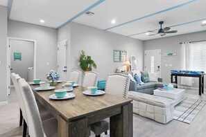A modern living room with a dining area, a sofa, a coffee table, and a ceiling fan. - Jackpot 6BR w/ Arcade • Vegas Fun Near the Strip (North Las Vegas)